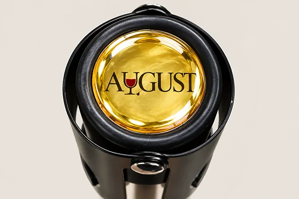 Custom AUGUST logo on a gold decorative top of a champagne bottle stopper
